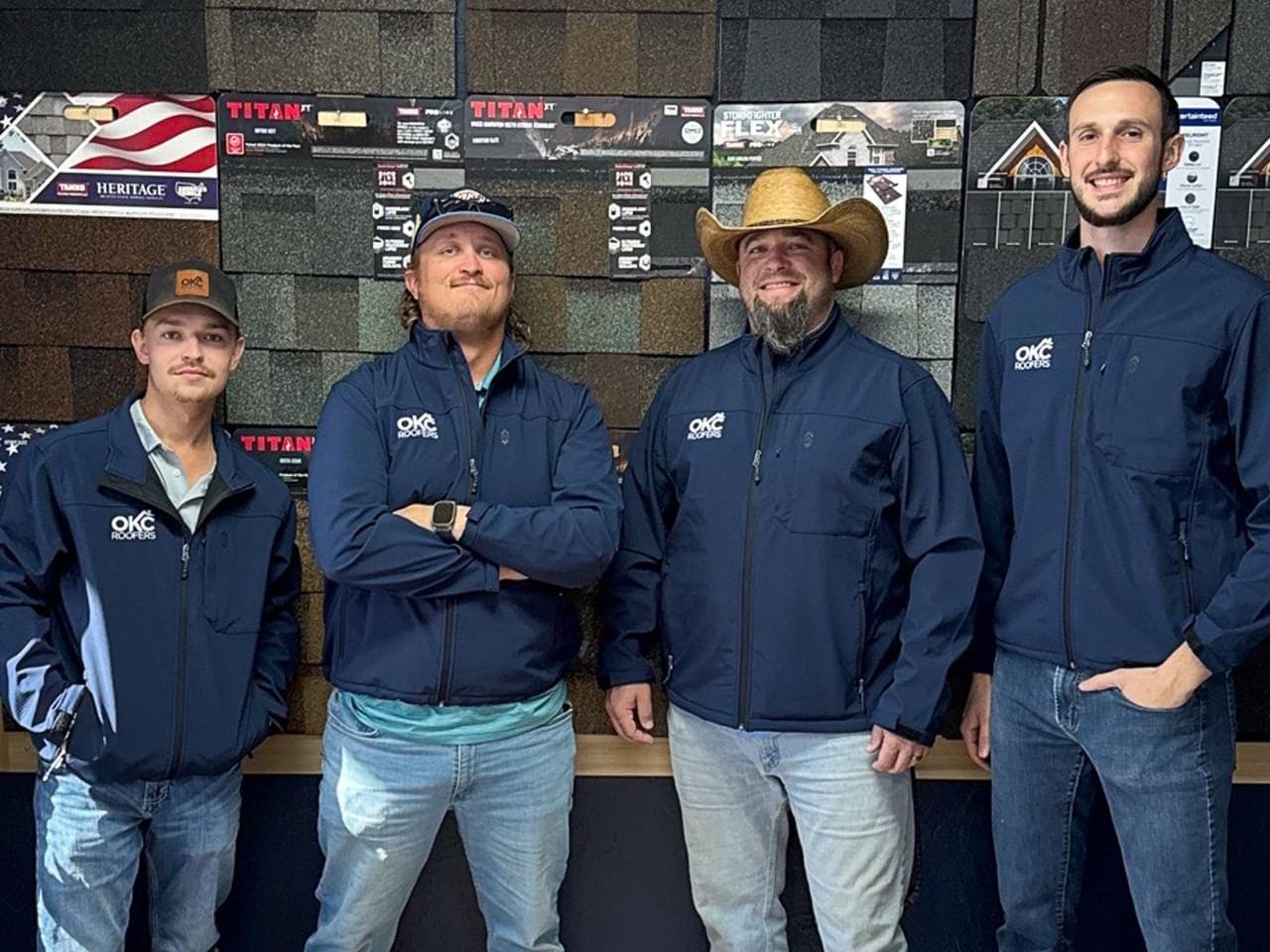 OKC Roofers leadership team at the Oklahoma City showroom standing in front of TAMKO Titan XT and Heritage shingle samples