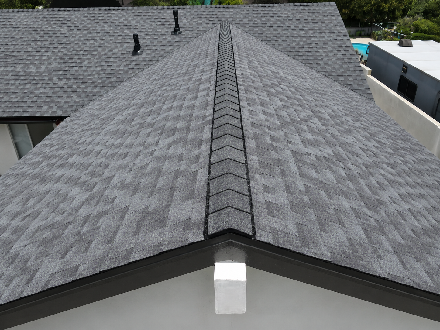 A close-up view of a gray asphalt shingle roof showing the ridge cap