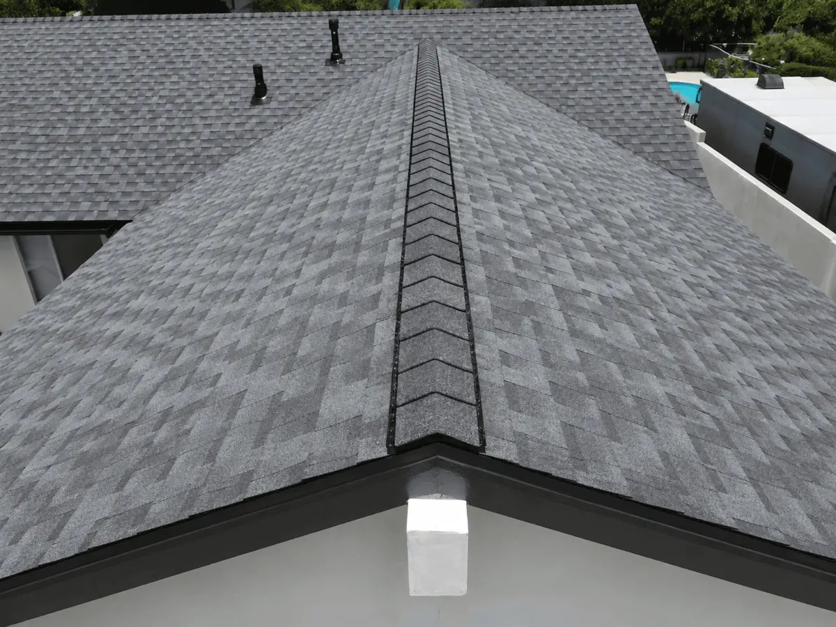 A close-up view of a gray asphalt shingle roof showing the ridge cap