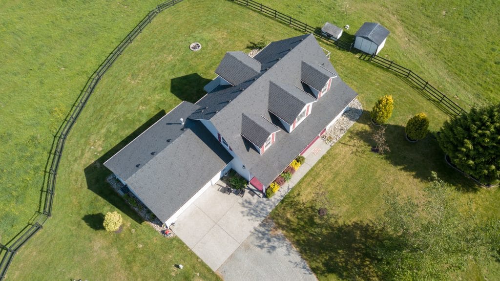 Drone photo of single family house with grey roof and large green grass yard.