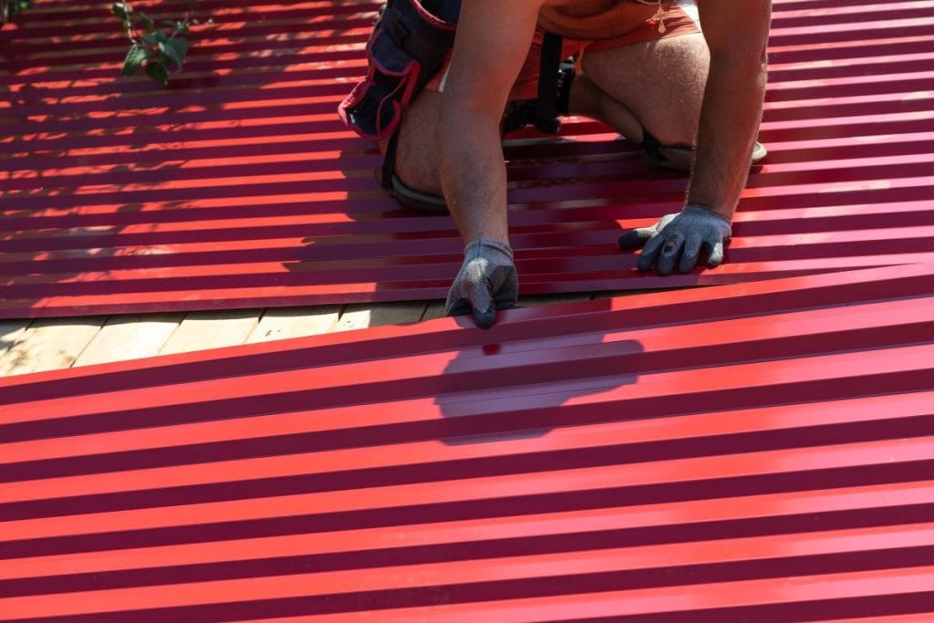 guy installing corrugated red metallic panels